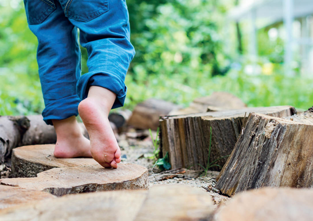 Kind begeht Barfuß einen Holz-Parcour.
