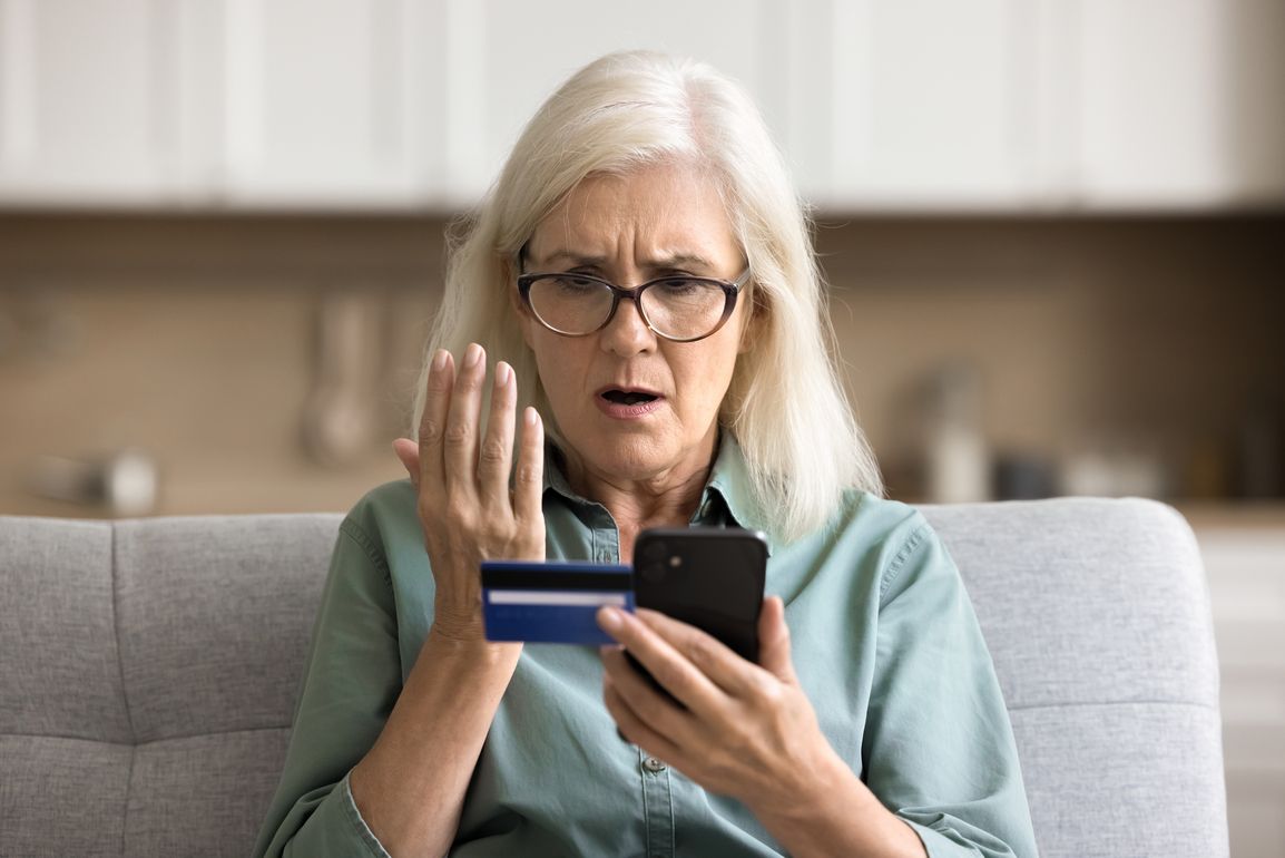 Erschrockene Frau mit Handy in der Hand